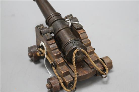 An early 20th century bronze model of a Naval cannon, on wooden trunnion base, length 25cm